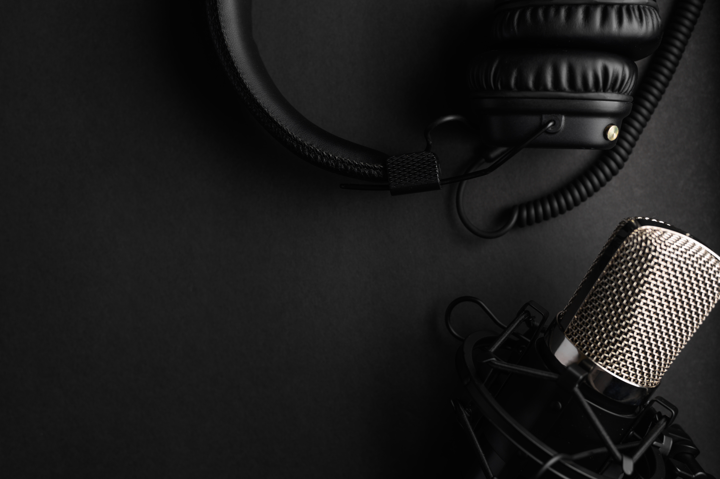 Studio black studio microphone with studio headphones on a black background. Banner. Radio, work with sound, podcasts.